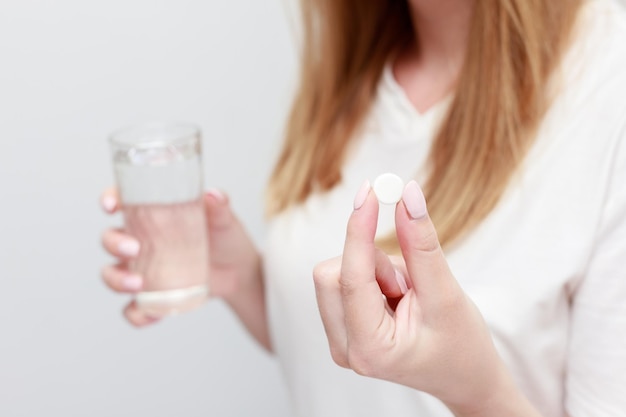 Una tableta en la mano y un vaso de agua de cerca