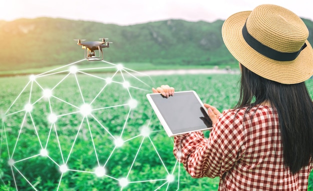 Tableta en manos de los agricultores tecnología drones para controlar los productos agrícolas