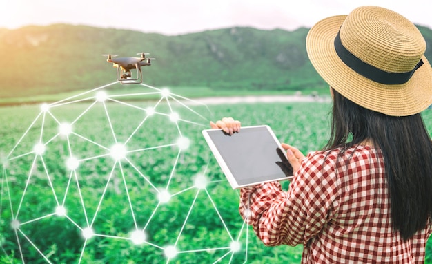 Foto tableta en manos de los agricultores tecnología drones para controlar los productos agrícolas