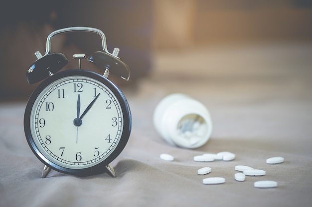 Tableta de medicina y reloj de escritorio en la cama