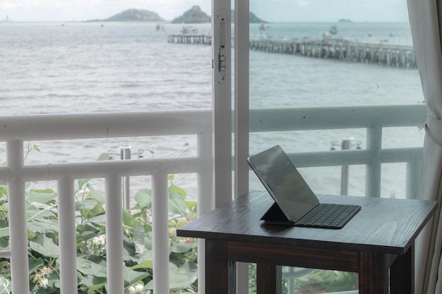 Tableta en la mesa en el balcón de la habitación del hotel con vista al mar