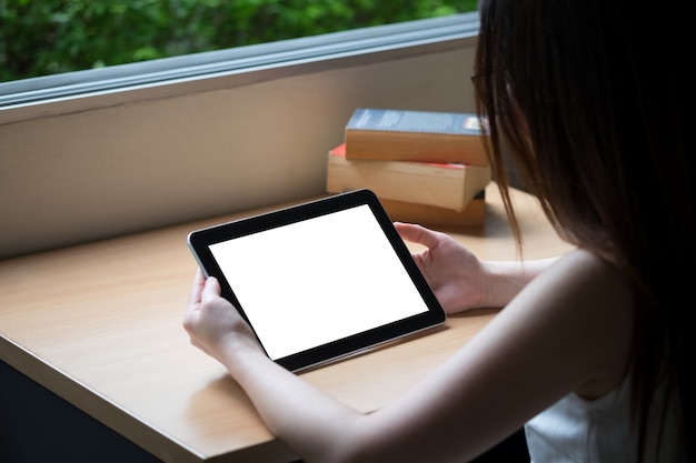 Tableta en la mesa de madera con el libro viejo