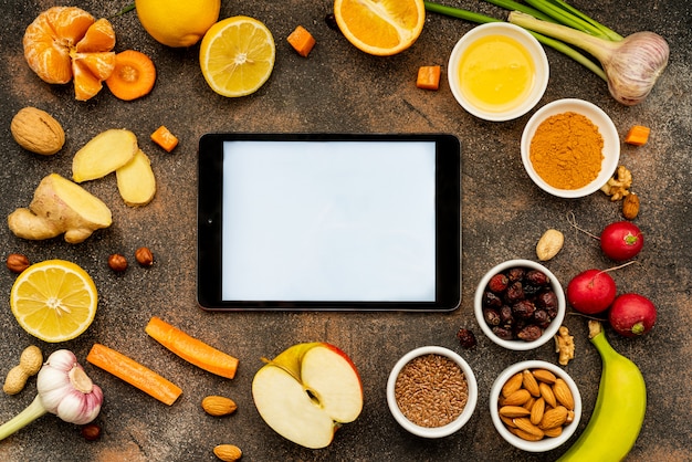 Foto una tableta con una pantalla blanca alrededor de alimentos saludables para mejorar la inmunidad. vista superior, copia espacio.