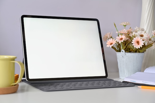 Tableta de pantalla en blanco maqueta con teclado en el área de trabajo de estudio en casa