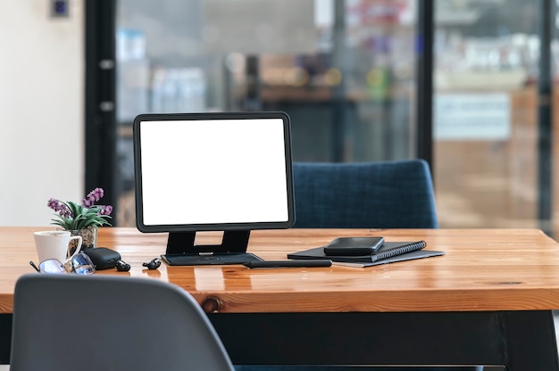 Foto tableta de pantalla en blanco con soporte y gadget en mesa de madera en co-workpace