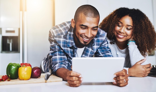 Tableta de pareja feliz y cocinando comida saludable con receta en la cocina en casa en el sitio web de Internet y conexión en línea Hombre mujer africana y tecnología para leer instrucciones en el blog de comida vegana