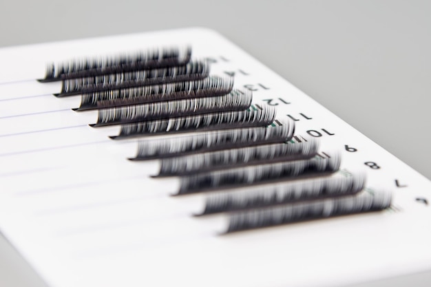 Una tableta con pestañas postizas sobre un fondo gris Accesorios cosméticos para extensiones de pestañas