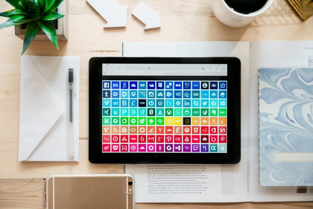 Tableta que muestra una cuadrícula colorida de iconos de aplicaciones en un escritorio de madera