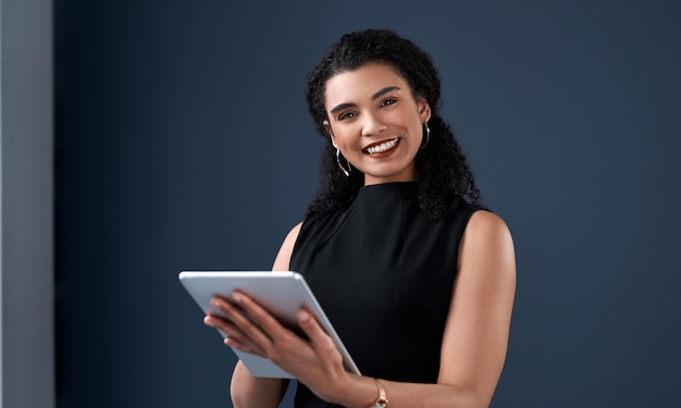 Tableta y retrato de mujer de negocios en el estudio con sonrisa, felicidad y aplicación para el trabajo de la compañía Tecnología y cara de empleada corporativa en fondo azul con correo electrónico de investigación e internet para el trabajo