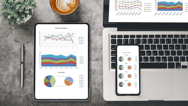 Tableta y teléfono inteligente con gráficos e informes en el lugar de trabajo de escritorio de la oficina Vista superior plana layx9