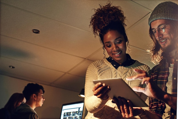 Tableta de trabajo en equipo e idea con personas en la oficina por la noche para planificar el diseño y la estrategia web Colaboración creativa y tecnología con hombres y mujeres en el inicio para la investigación y la propuesta de datos