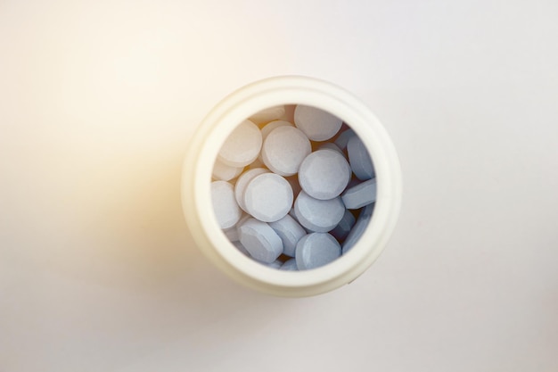 Tabletas azules en frasco de plástico blanco en concepto de farmacia de atención médica cerrada