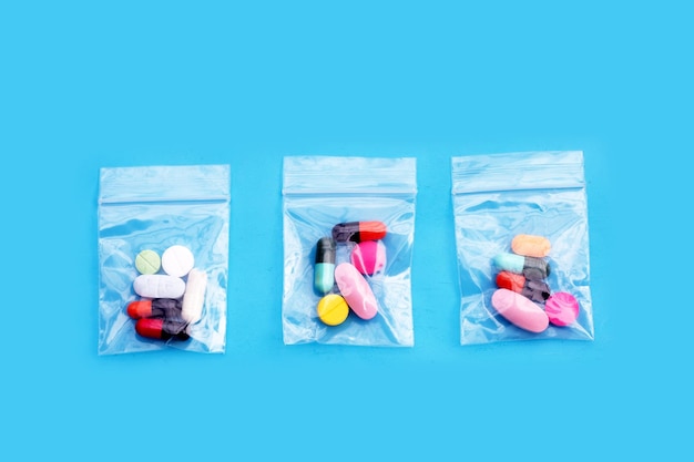 Tabletas de colores con cápsulas y píldoras en bolsas de plástico con cierre de cremallera de medicina sobre fondo azul Vista superior