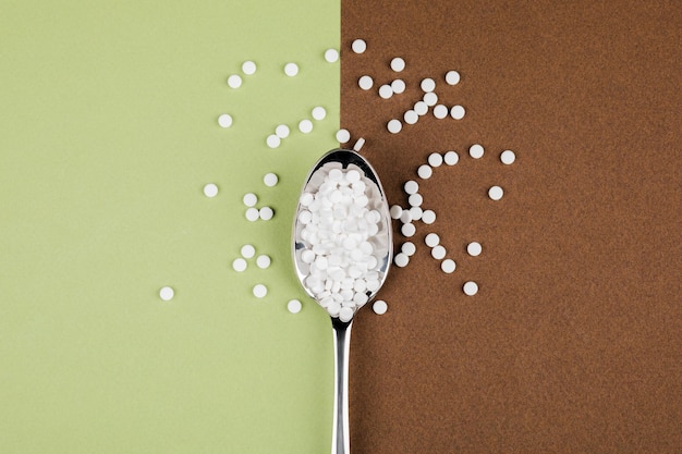 Foto tabletas de reemplazo de azúcar con una cuchara sobre un fondo marrón verde
