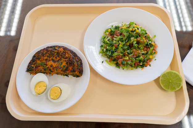 Tablett-Menü mit Karotten-Omelette gekochtem Ei und Salattellern Mittagspause im Fabrikkonzept