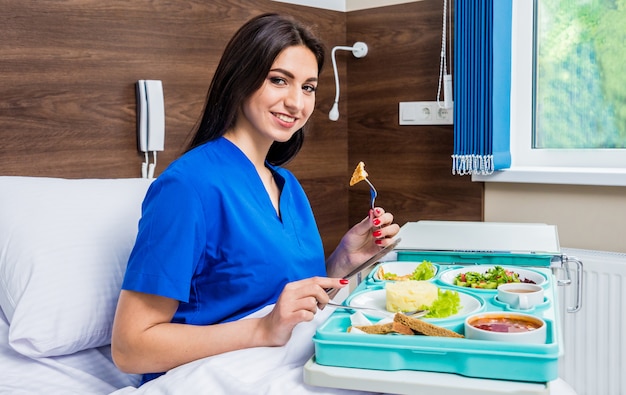 Tablett mit Frühstück für die junge Patientin. Die junge Frau, die im Krankenhaus isst.