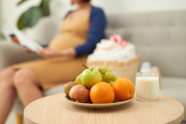 Tablett mit gesundem Frühstück und unscharfer schwangerer Frau im Hintergrund