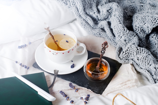 Tablett mit Honig und einer Tasse heißen Tee im Bett