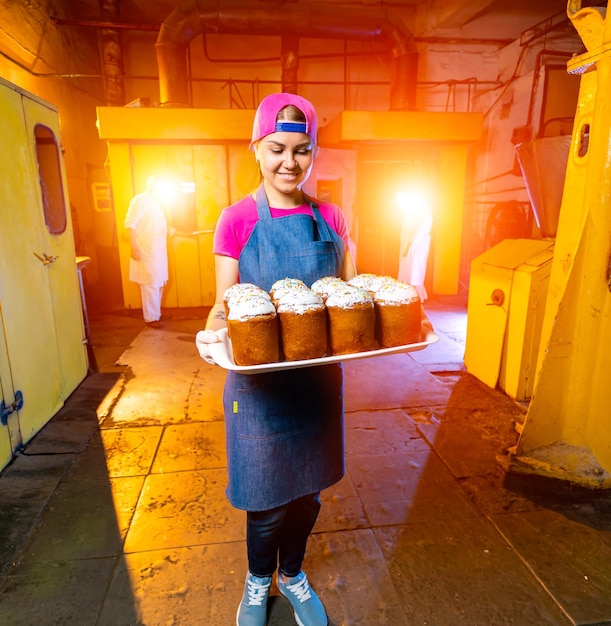 Tablett mit Osterkuchen in der Industriebäckerei Hintergrundtextur Frau hält Tablett mit frischen Backwaren