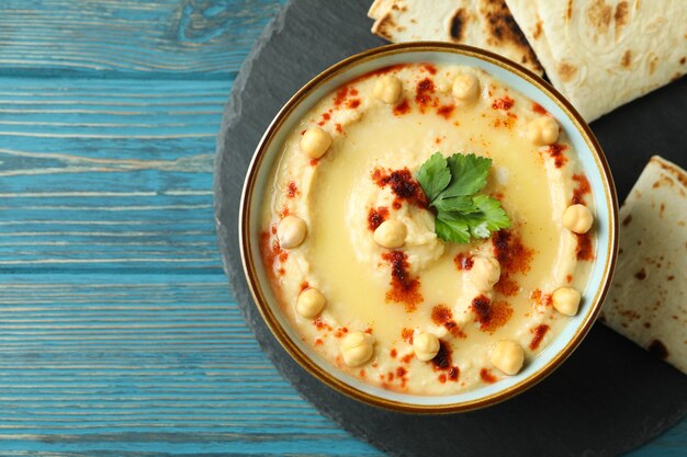 Tablett mit Schüssel Hummus und Pita auf Holztisch