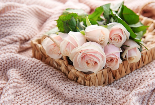 Tablett mit Strauß schöner rosa Rosen und Geschenkbox auf dem Bett