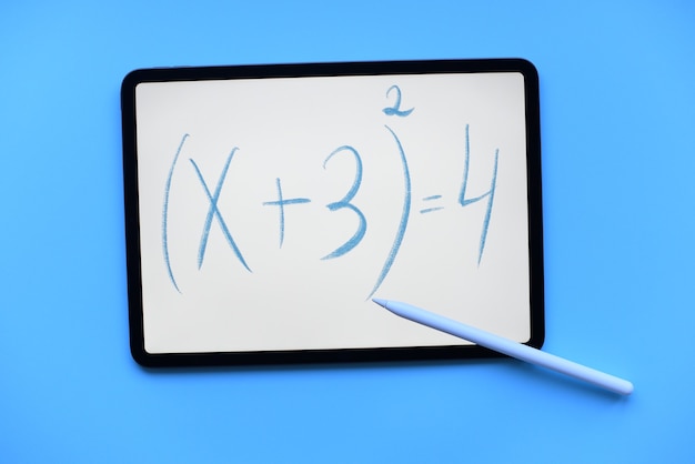 Tablette ipad mit der mathematischen Gleichungsbeschriftung mit Apfelstift und auf blauem Hintergrund