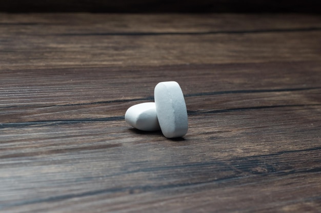 Tabletten mit medizinischen Pillen auf einem bewaldeten Tisch.