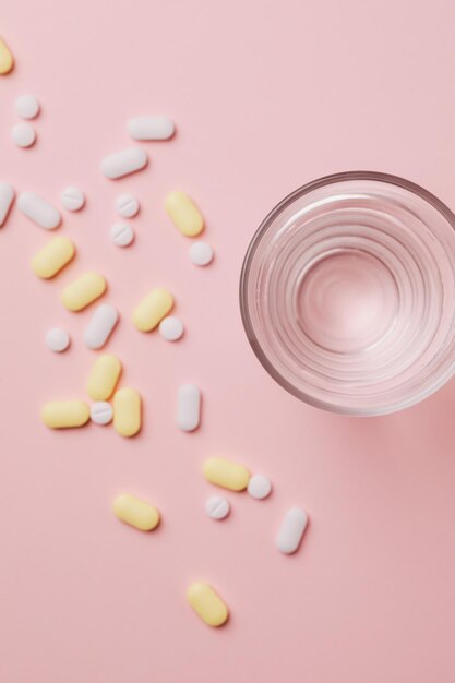 Tablettenfläschchen verschüttet. bunte Pillen Kapsel auf Oberfläche Tabletten mit einem Glas Wasser