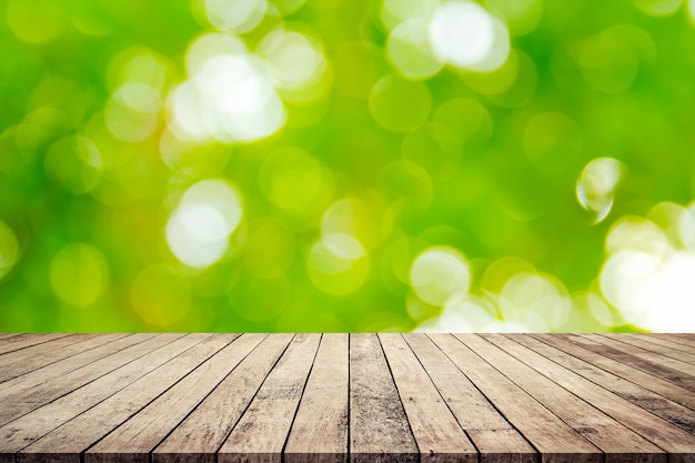 Tablón de madera viejo con el fondo borroso verde natural abstracto del bokeh para la exhibición del producto