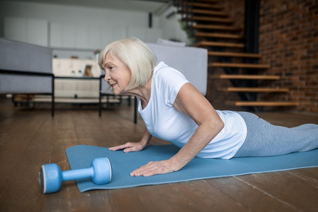 Tablón. Senior mujer activa en una camiseta blanca haciendo tablón