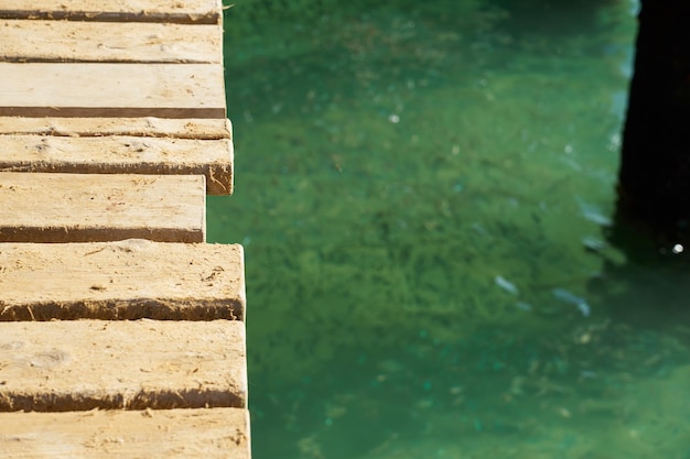 Tablones de madera del viejo puente con agua borrosa en el fondo