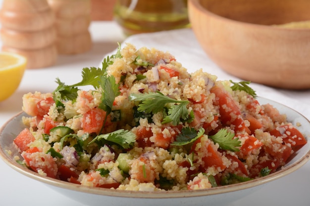 Foto taboulé ist ein vegetarischer salat der küche des nahen ostens mit gehackter petersilie, tomaten, minze, zwiebeln und bulgur, gewürzt mit olivenöl, zitronensaft