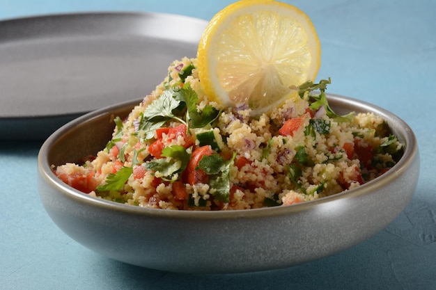 Foto taboulé ist ein vegetarischer salat der küche des nahen ostens mit gehackter petersilie, tomaten, minze, zwiebeln und bulgur, gewürzt mit olivenöl, zitronensaft