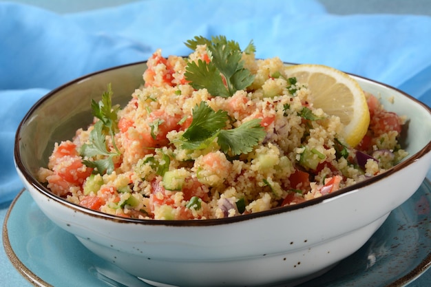 Foto taboulé ist ein vegetarischer salat der küche des nahen ostens mit gehackter petersilie, tomaten, minze, zwiebeln und bulgur, gewürzt mit olivenöl, zitronensaft