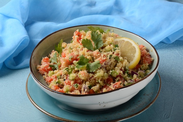 Taboulé ist ein vegetarischer Salat der Küche des Nahen Ostens mit gehackter Petersilie, Tomaten, Minze, Zwiebeln und Bulgur, gewürzt mit Olivenöl, Zitronensaft