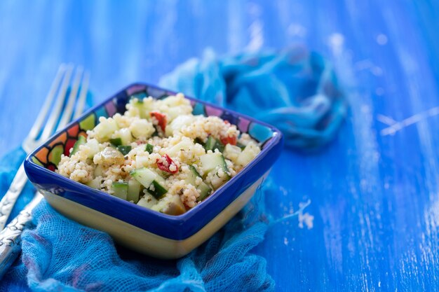 Tabouleh in der kleinen Schüssel auf blauem hölzernem Hintergrund