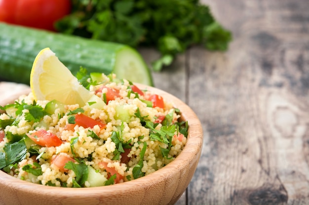 Tabouleh-Salat mit Couscous in der hölzernen Schüssel auf rustikaler Tabelle