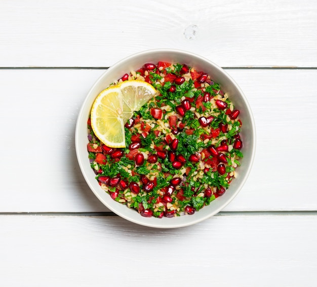 Taboulehsalat mit Bulgur, Minze, Petersilie, Tomaten und Granatapfel. Gesundes Essen. Vegetarisches Essen.