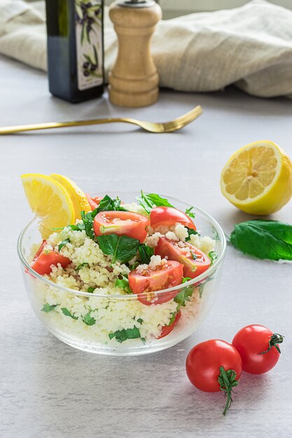 Tabouli caseiro fresco ou salada de tabule com vista lateral de seus ingredientes na superfície cinza