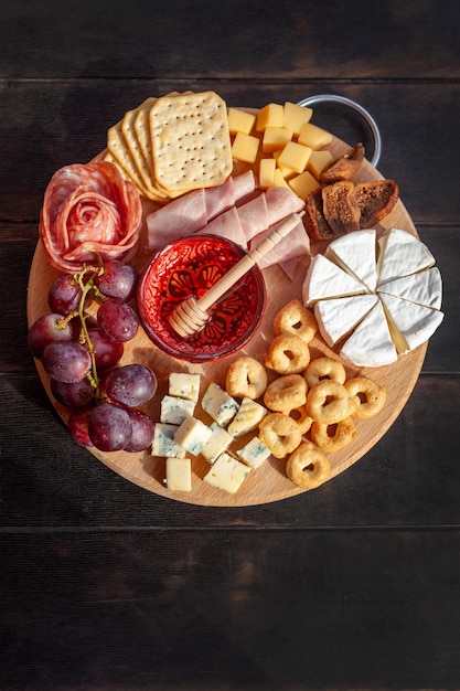 Tábua de aperitivos com queijo sortido carne linguiça roseta uva e biscoitos salgados