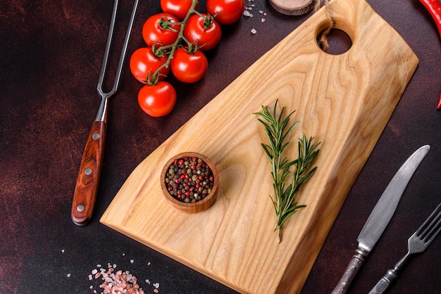 Tábua de cortar com sal, especiarias e ervas em um fundo escuro de concreto. Cozinhando Alimentos Saudáveis