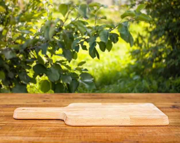 tábua de cortar na mesa de madeira ao ar livre com fundo de pomar de maçã
