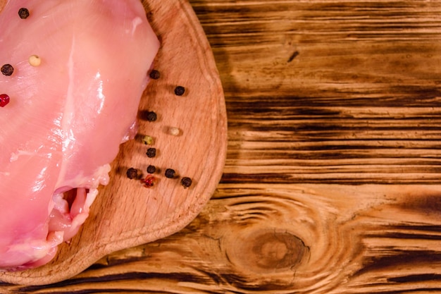 Tábua de corte com filé de frango cru e especiarias diferentes na mesa de madeira Vista superior