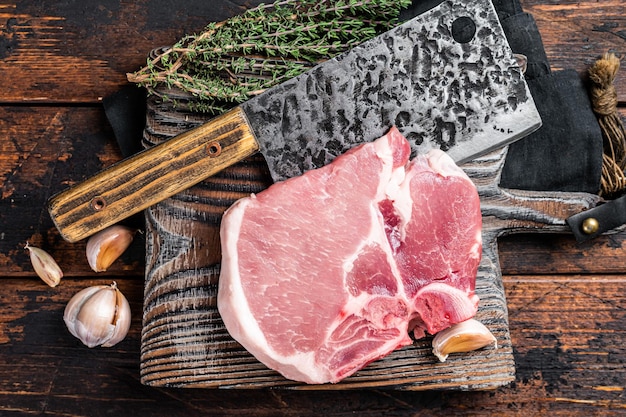 Tábua de corte de açougueiro com bife de carne de porco Tbone cru Fundo de madeira Vista superior