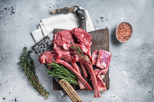 Tábua de corte de açougueiro com bife de costeleta de cordeiro cru massacrado ou costeleta de carneiro Fundo cinza Vista superior