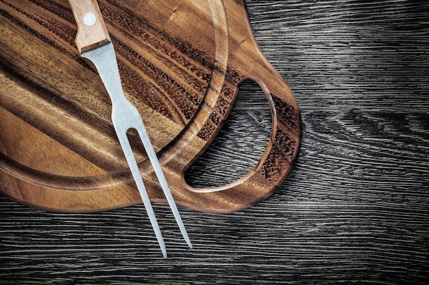 Foto tábua de corte de garfo de carne no fundo de madeira