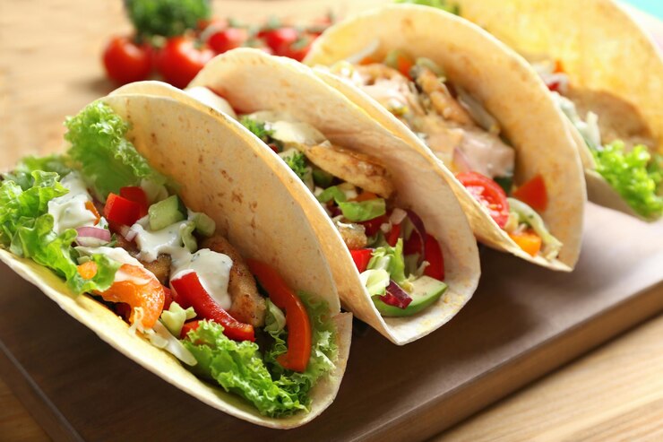 Tábua de madeira com saborosos tacos de peixe na mesa