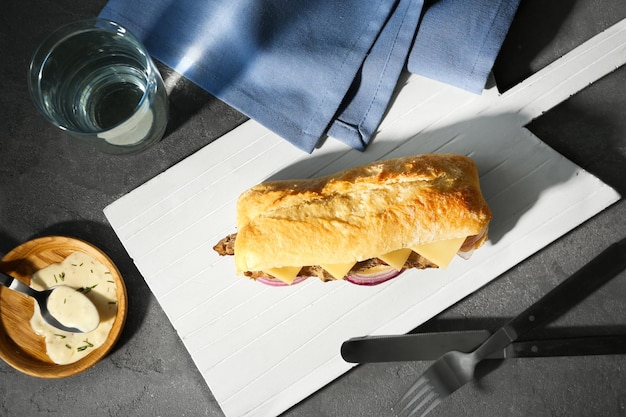 Tábua de madeira com sanduíche de bife na mesa