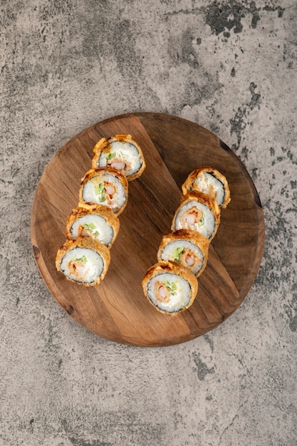 Tábua de madeira de sushi frito quente rola com salmão na superfície da pedra.