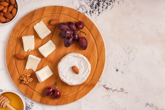 Tabuleiro com queijo, uvas, nozes e mel